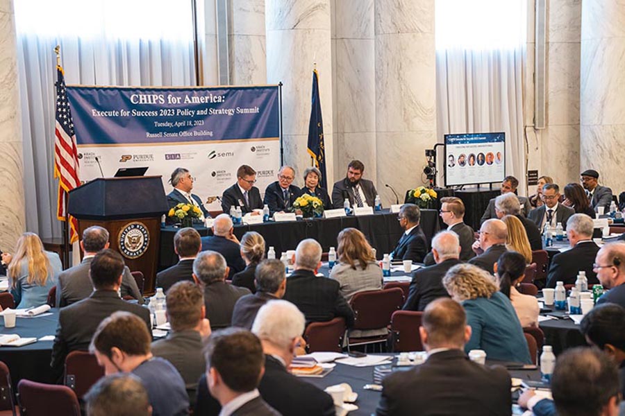 Mark Lundstrom sitting at a panel discussion during the CHIPS for America Conference, a crowd watches from the foreground