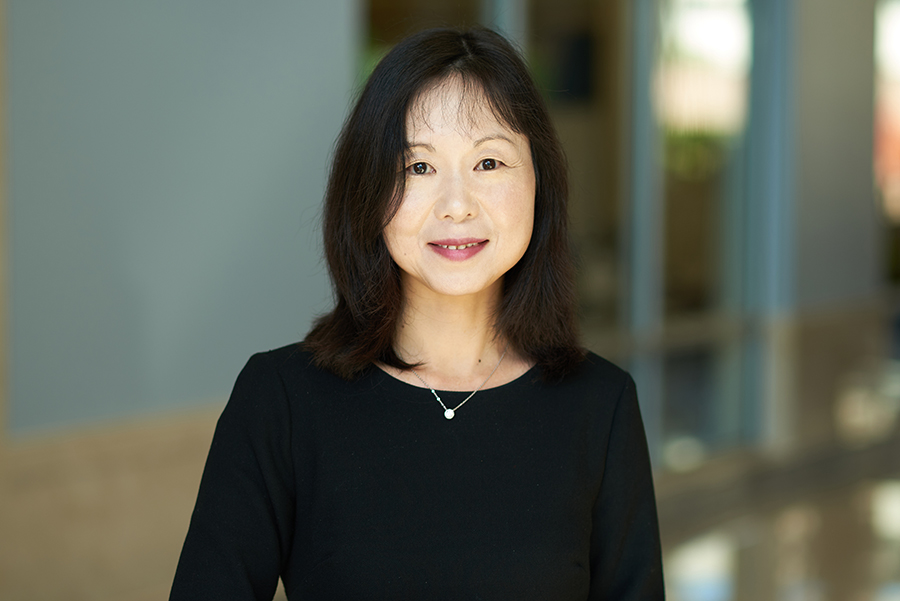 Portrait of Dan Jiao. She is standing in the MSEE atrium wearing a black top and necklace.