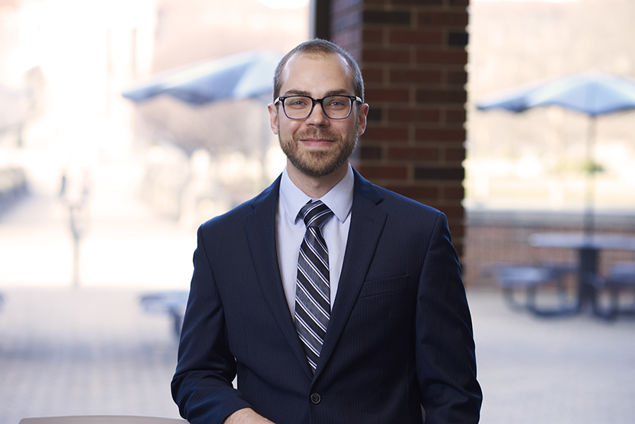 This is a portrait of Professor Thomas Roth. He has short cut hair along with a closely shaved beard. He is wearing glasses and suit with tie.