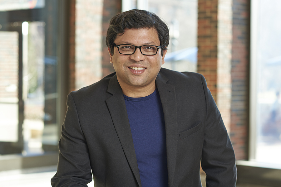 Photo of Professor Shreyas Sen. He is wearing a blue shirt with a black suit jacket.