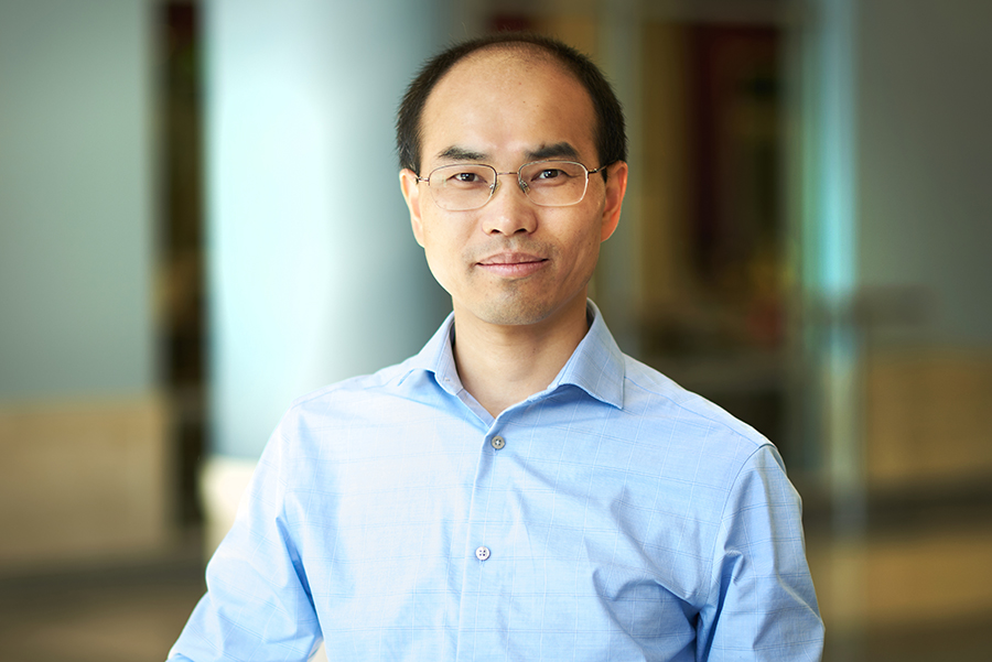 Tongcang Li poses for a portrait in the atrium of the MSEE building. He is wearing glasses and blue button up shirt.
