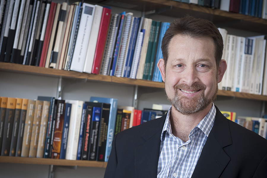 the late Professor Weiner poses for a portrait in front of a bookcase in his office.