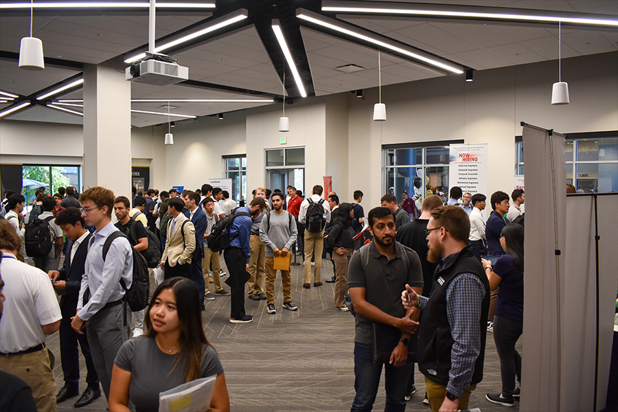 A large group of diverse individuals gathered together in a spacious room, engaged in conversation and interaction.