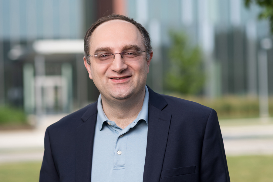 A man in glasses and a blue shirt standing outside