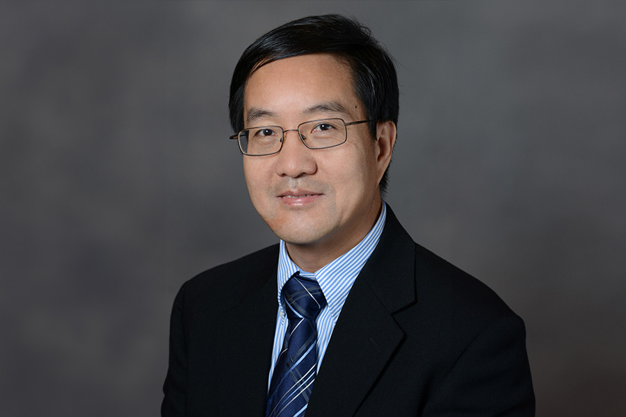 A well-dressed man in a suit and tie, sporting glasses, presents a polished and sophisticated image