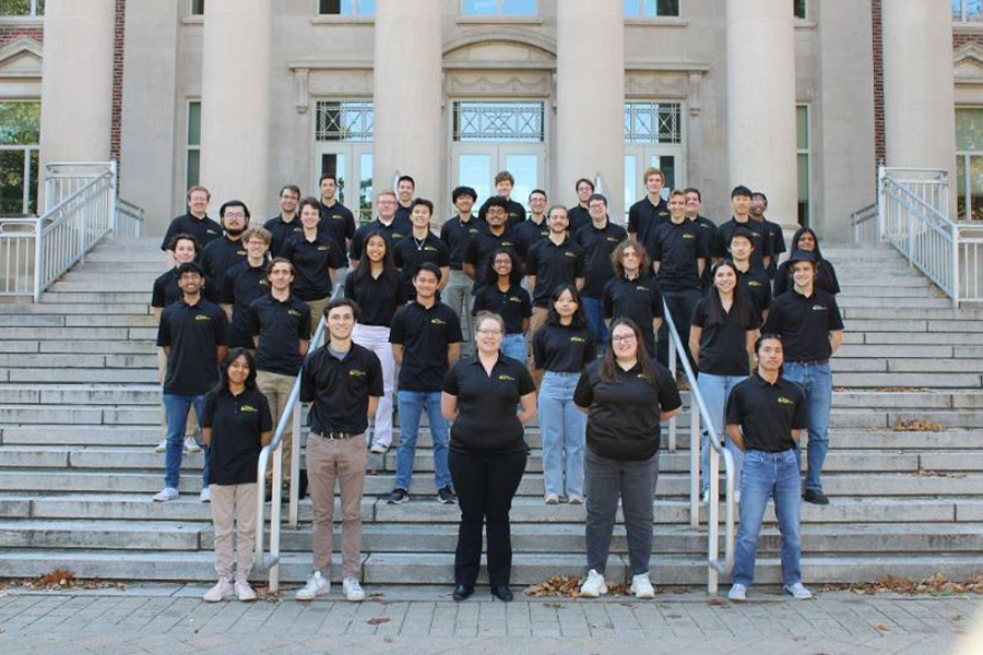 Members of Purdue Lunabotics, wearing branded black polos, pose of a group portrait on the steps of Hovde Hall.