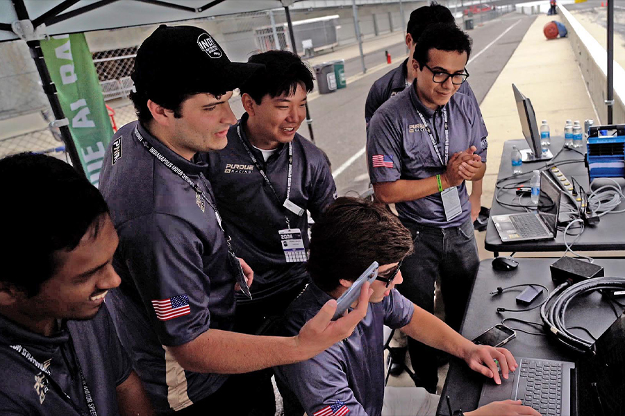 Several men dressed in grey shirts and black pants are engaged in work on their laptops, showcasing teamwork and productivity.