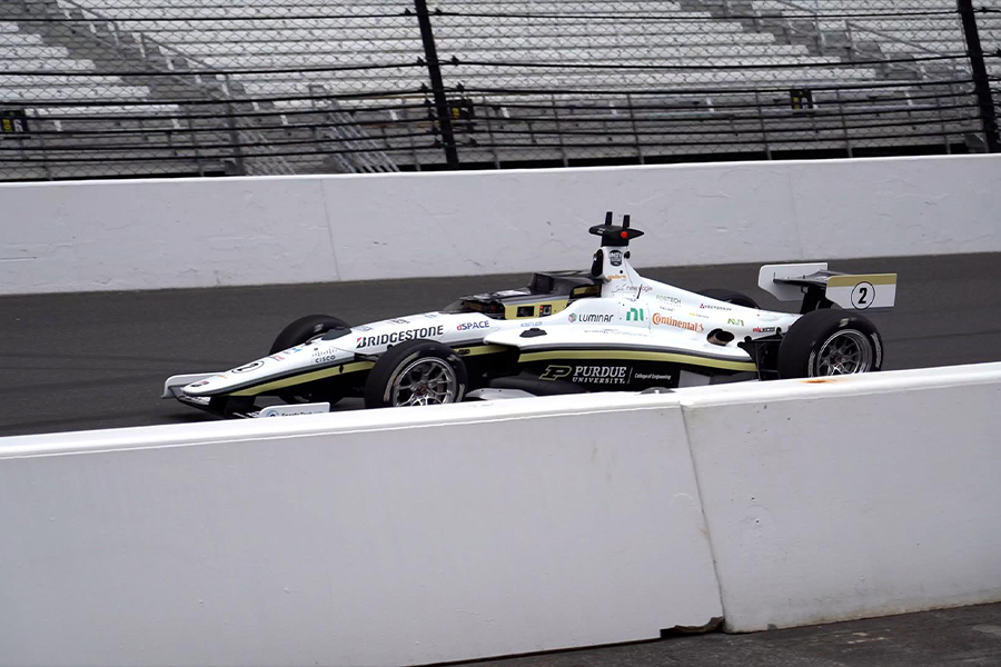A dynamic shot of a white and green racing car navigating a track, emphasizing its speed and aerodynamic features.