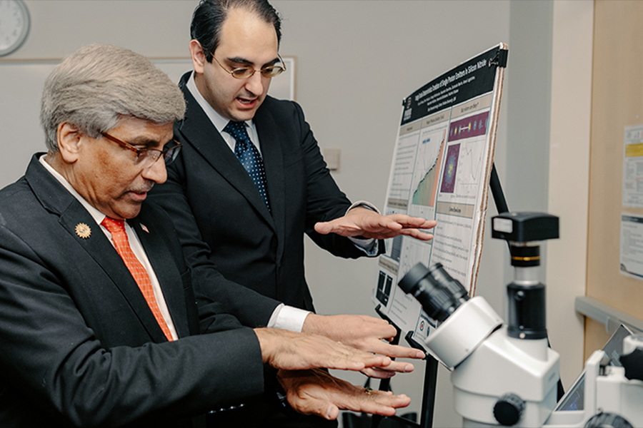 Two men in suits examining a microscope, engaged in discussion, showcasing a professional lab setting and collaboration.