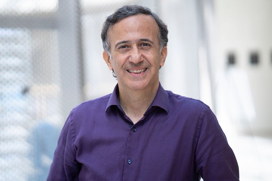 Ali Shakouri poses for a portrait in the Birck Nanotechnology Center. He is wearing a purple butotn up shirt.