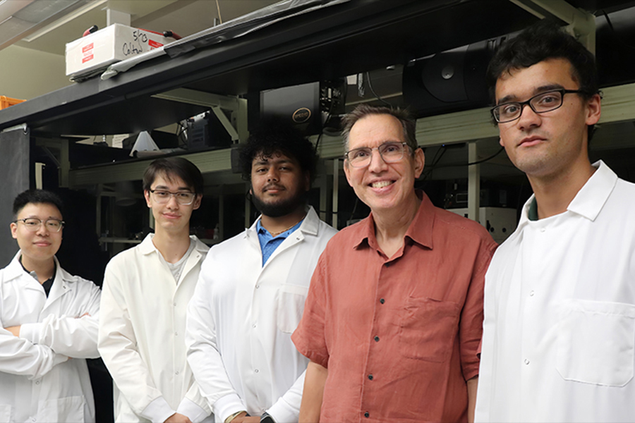  Several men in lab coats positioned side by side, representing teamwork in a laboratory setting.