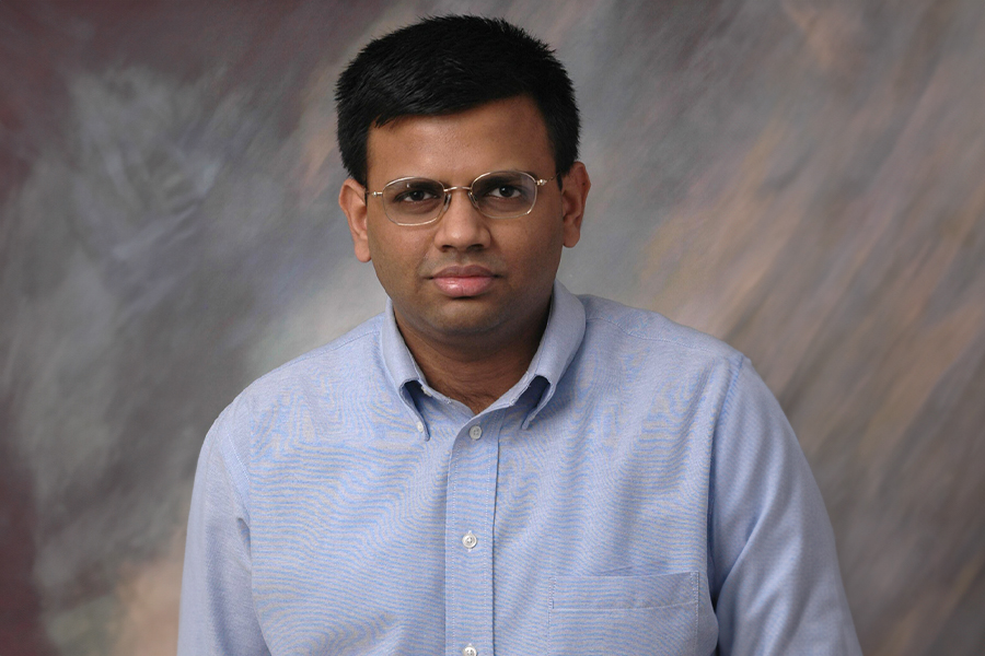 headshot of man wearing glasses and a blue shirt