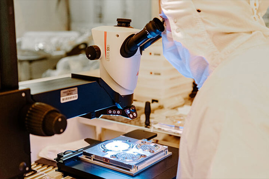 A researcher wearing a lab coat peers into a microscope, engaged in scientific analysis and exploration