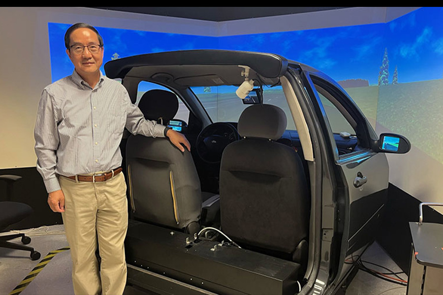 A man stands before a car, focused on a computer screen, illustrating the connection between automotive and digital technology