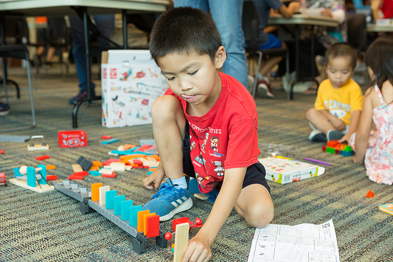 Young boy playing on the floor with an engineering-inspired toy