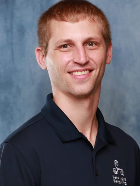 Man with brown eyes, wearing blue shirt, smiling