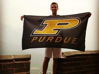 Student standing on the Great Wall holding a Purdue Flag