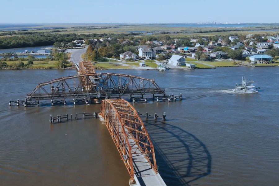 A boat passes through the Chef Menteur Pass Bridge, with New Orleans off in the distance
